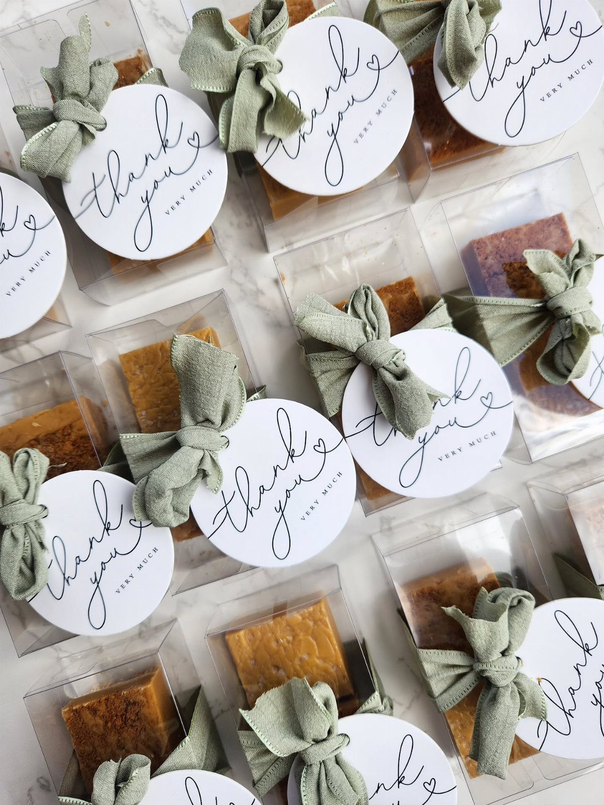 Handmade soap bars in clear packets with sage green bows and thank you tags.