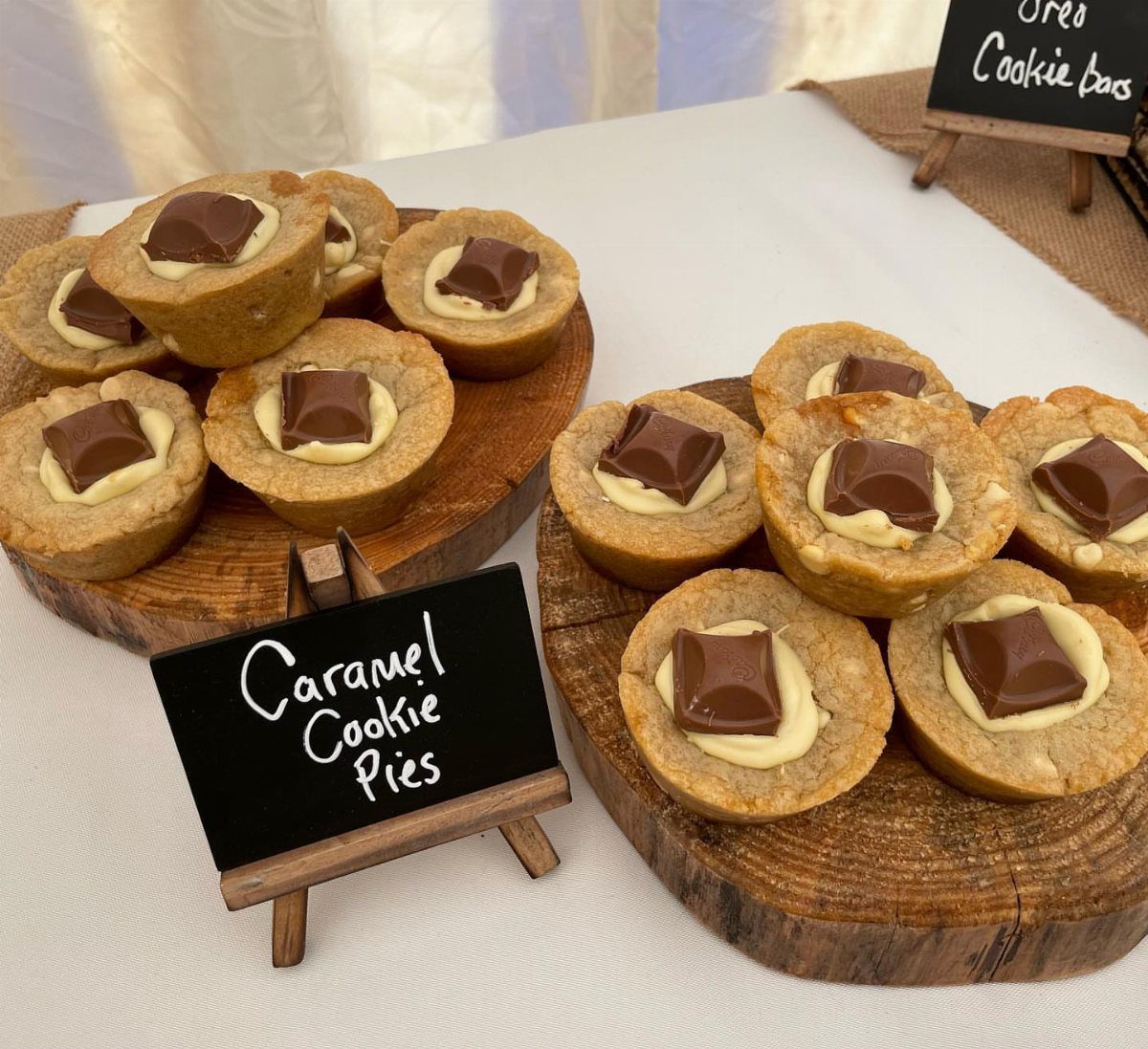 Caramel cookie pies with chocolate squares on rustic wooden serving platters.