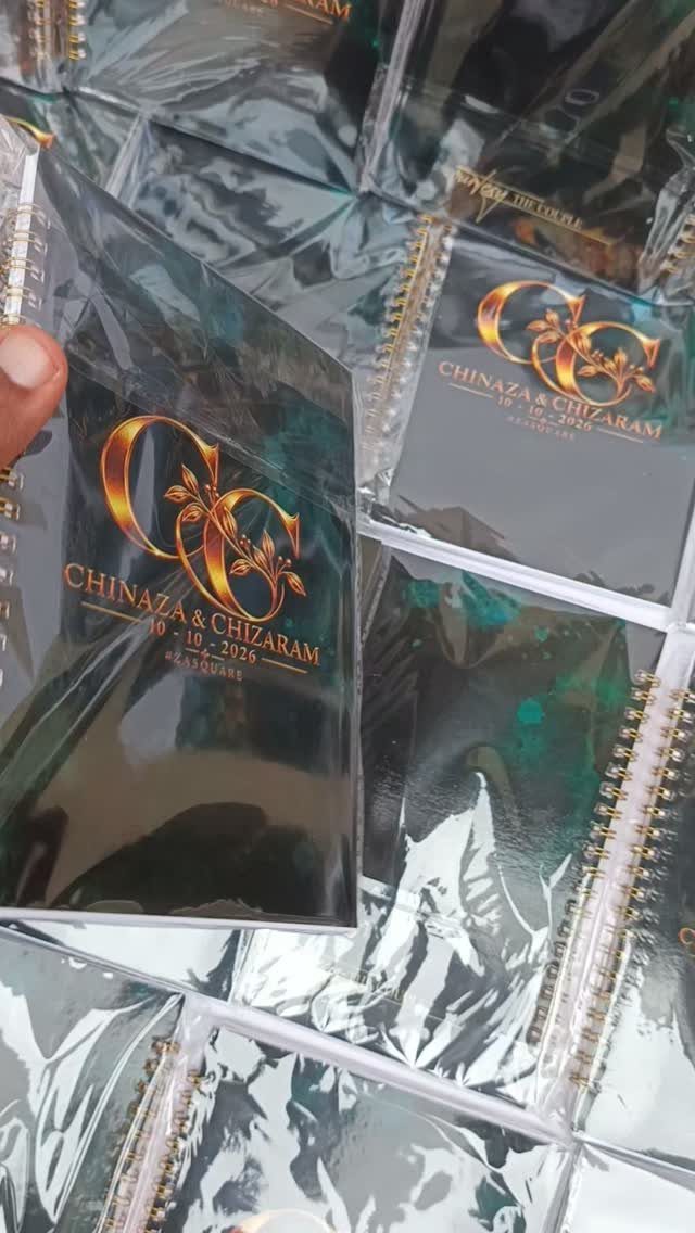 Black spiral notebooks with gold personalized text wrapped in clear plastic packaging.