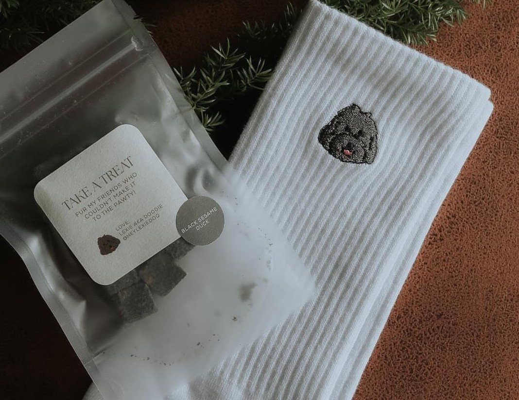 Plastic bag of dog treats and a white towel with dog embroidery.