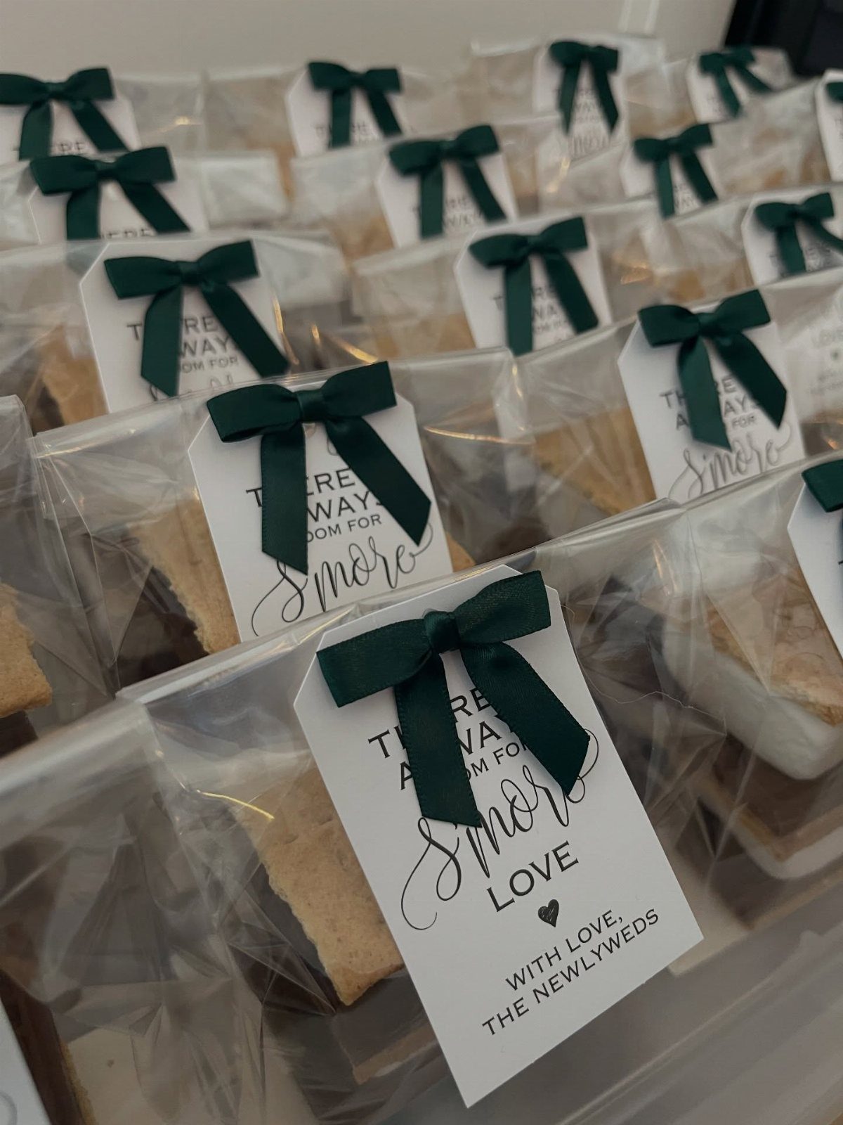 Smores kits in clear bags with green ribbons and personalized wedding favor tags.