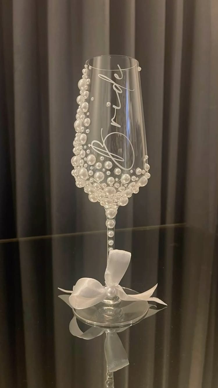 Champagne flute decorated with white pearls and a bow, labeled Bride in cursive.
