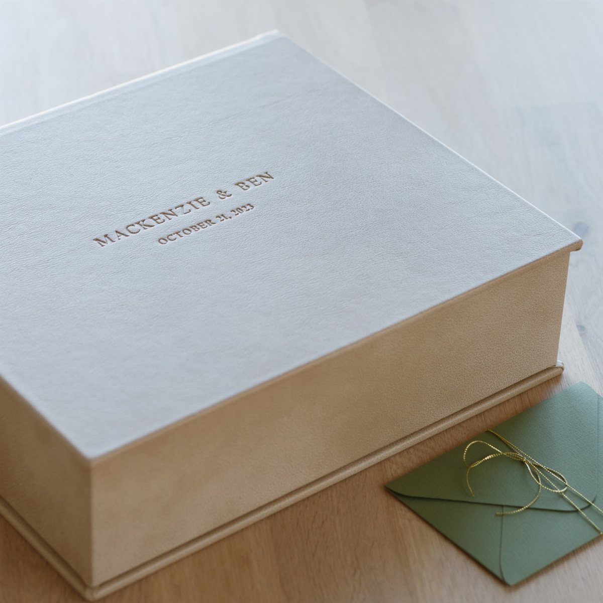 Personalized grey fabric wedding keepsake box with embossed names and date on wooden surface