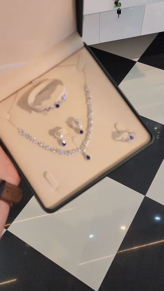 Jewelry set with blue accents in a black box on checkered flooring