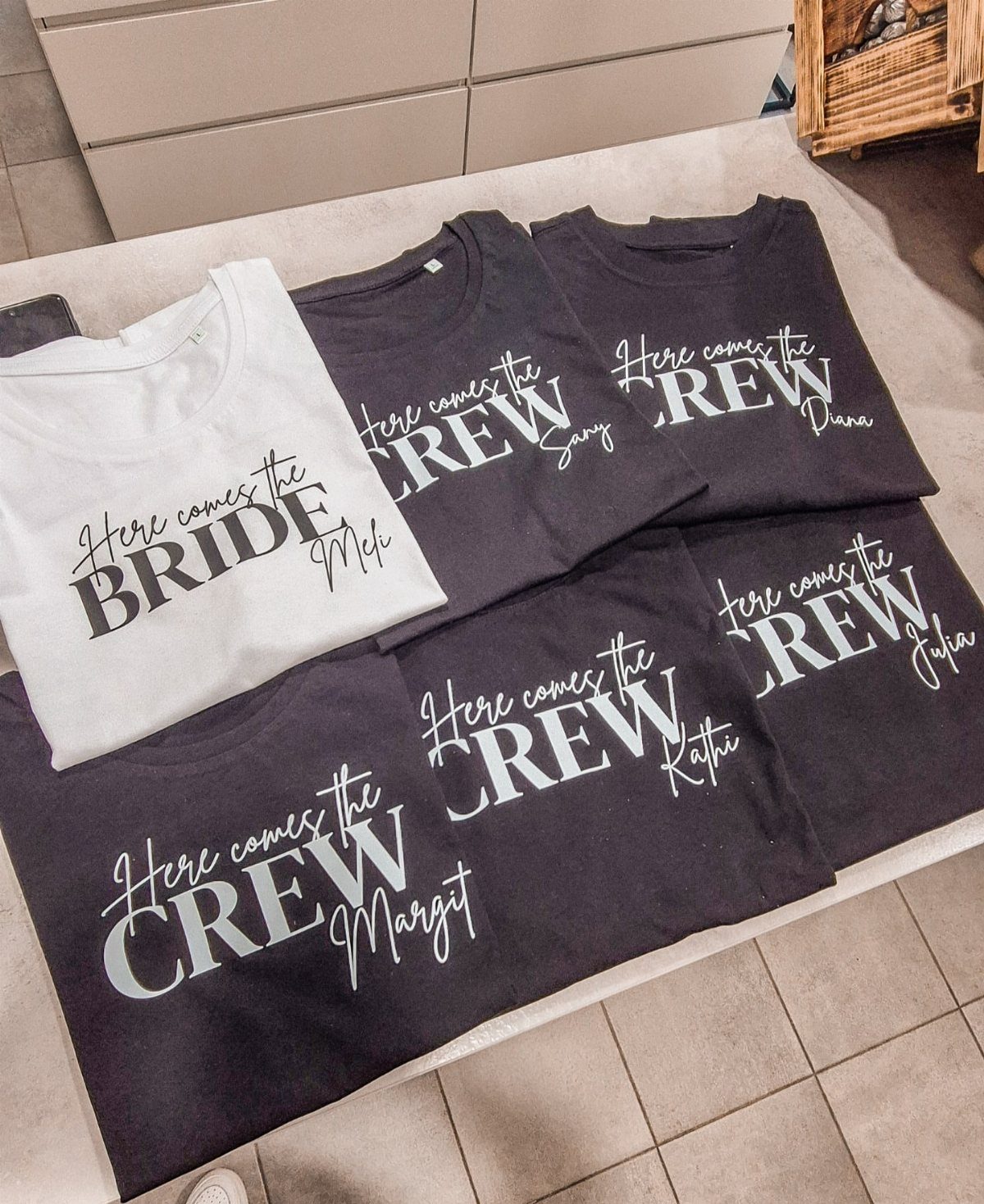 White bride t-shirt and black bridesmaid crew t-shirts laid on a table