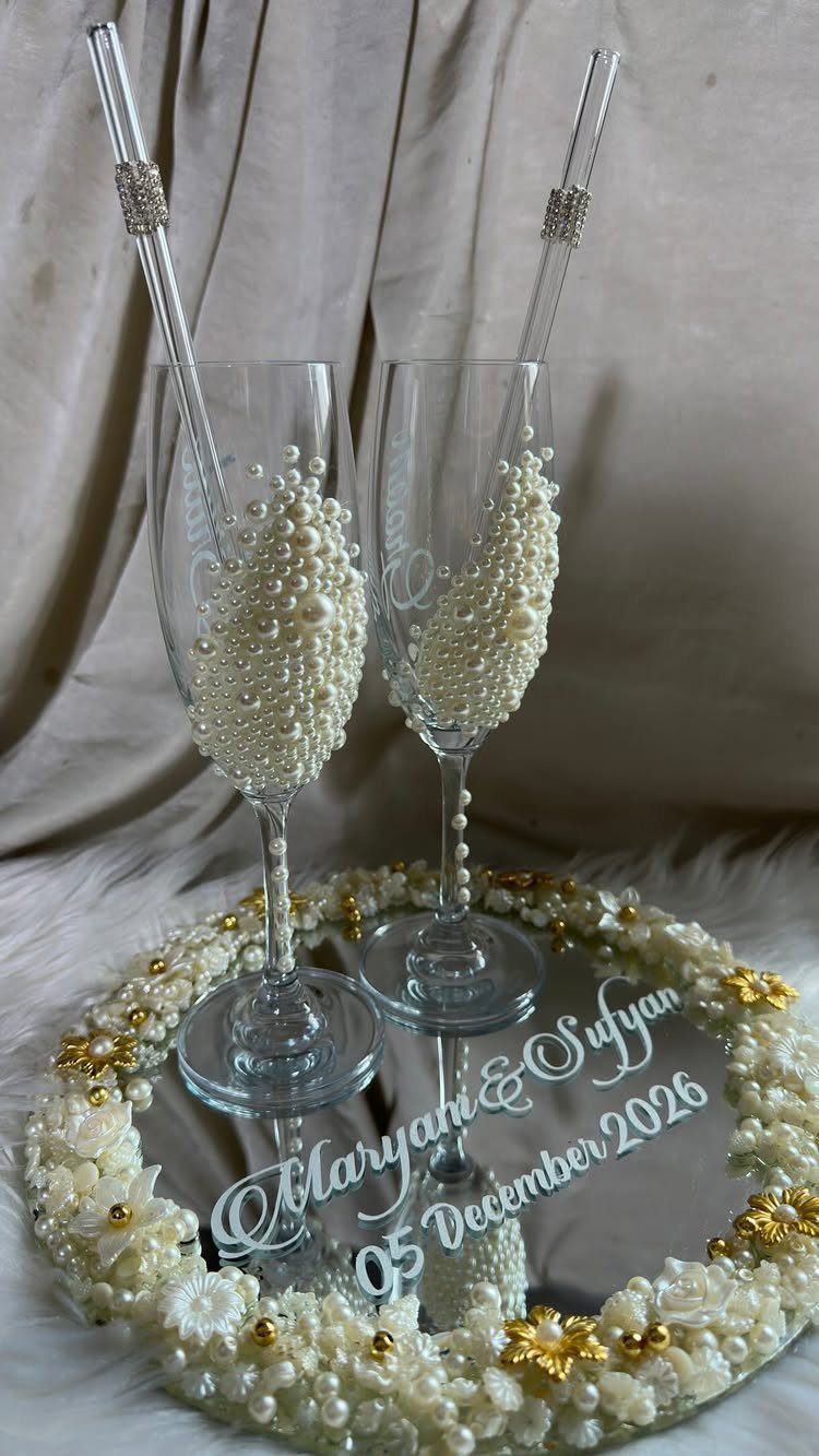 Pearl decorated champagne flutes on a mirrored tray with white floral borders