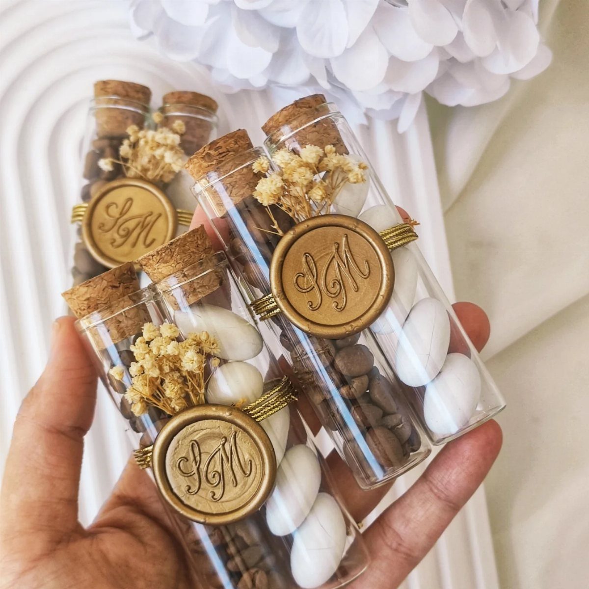 Glass vials filled with chocolate covered almonds decorated with gold wax seals.