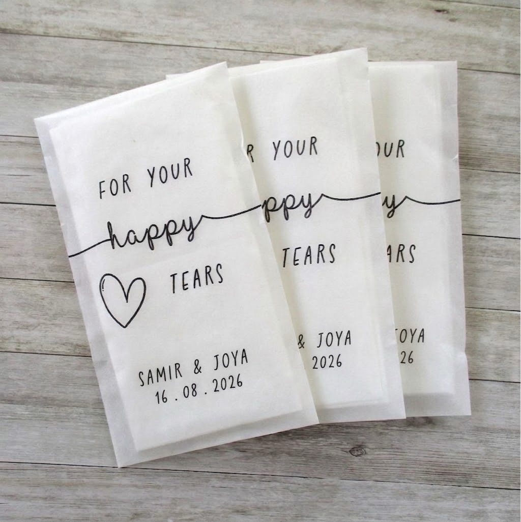Three white tissue packets with happy tears text on a wooden background