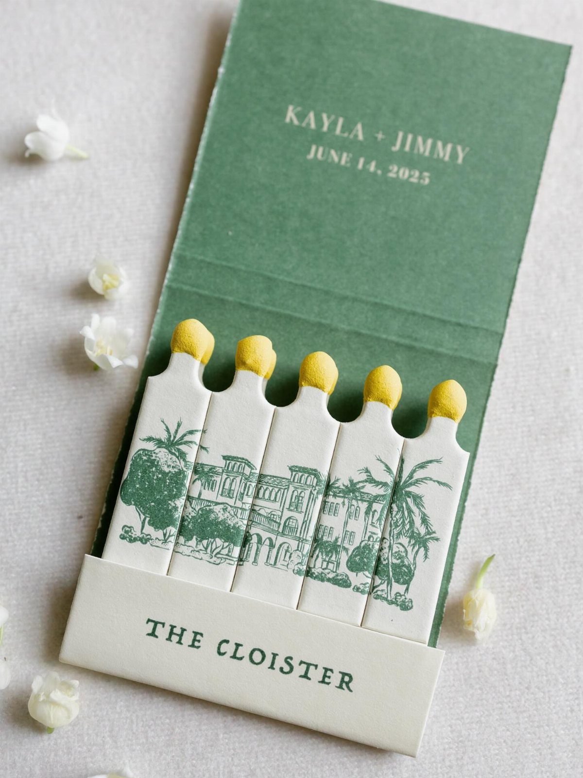 Personalized green matchbook with custom illustration and wedding names on a white surface.
