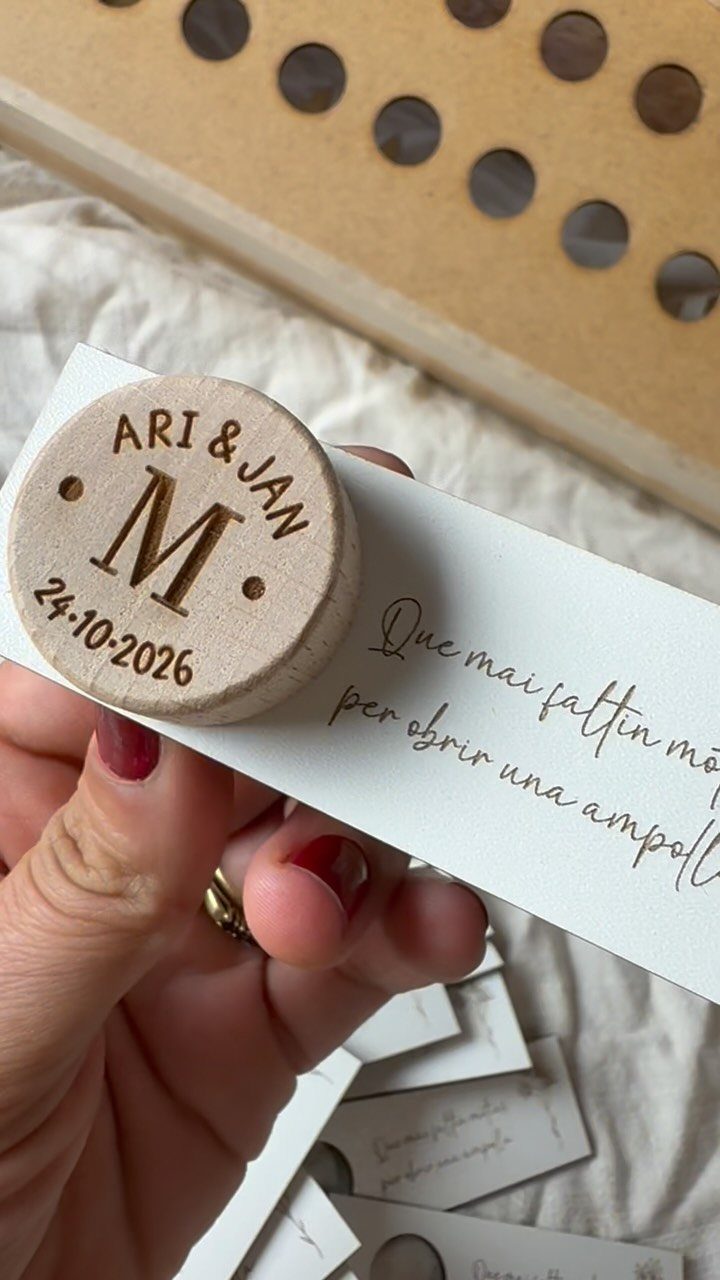 Wooden wine bottle stopper engraved with names and date on a white card