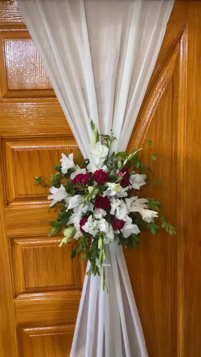 White and red flower bouquet tied to a white sheer curtain on a door