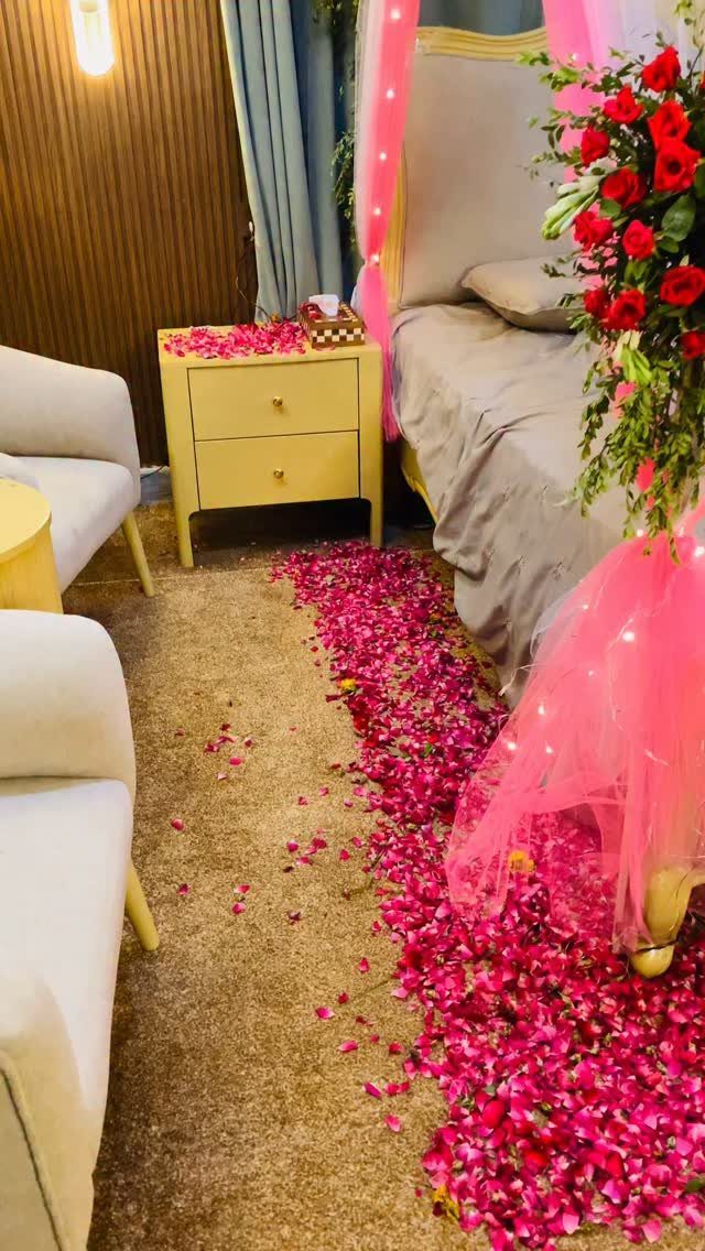 Pink rose petal walkway on a beige carpet leading to a decorated bed.