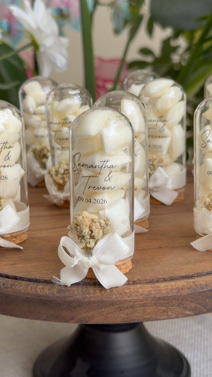 Small glass dome jars with white candies and ribbons on a wooden stand
