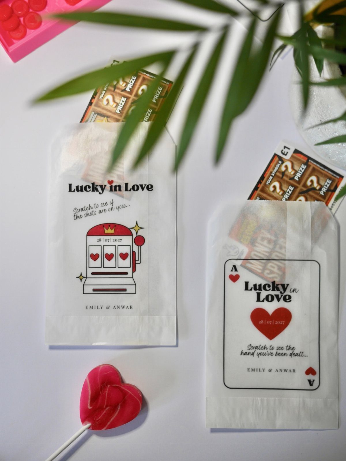 White paper gift bags with lottery scratch cards and heart-shaped lollipop on white background