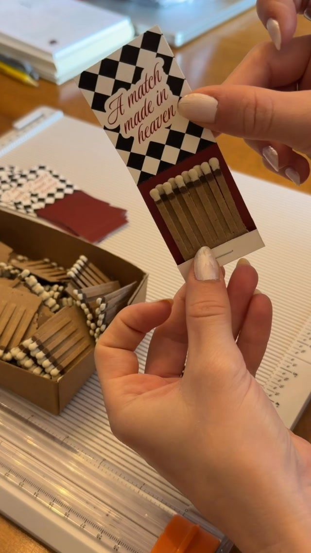 Custom wedding matchbook with checkered border and romantic text held by hands.