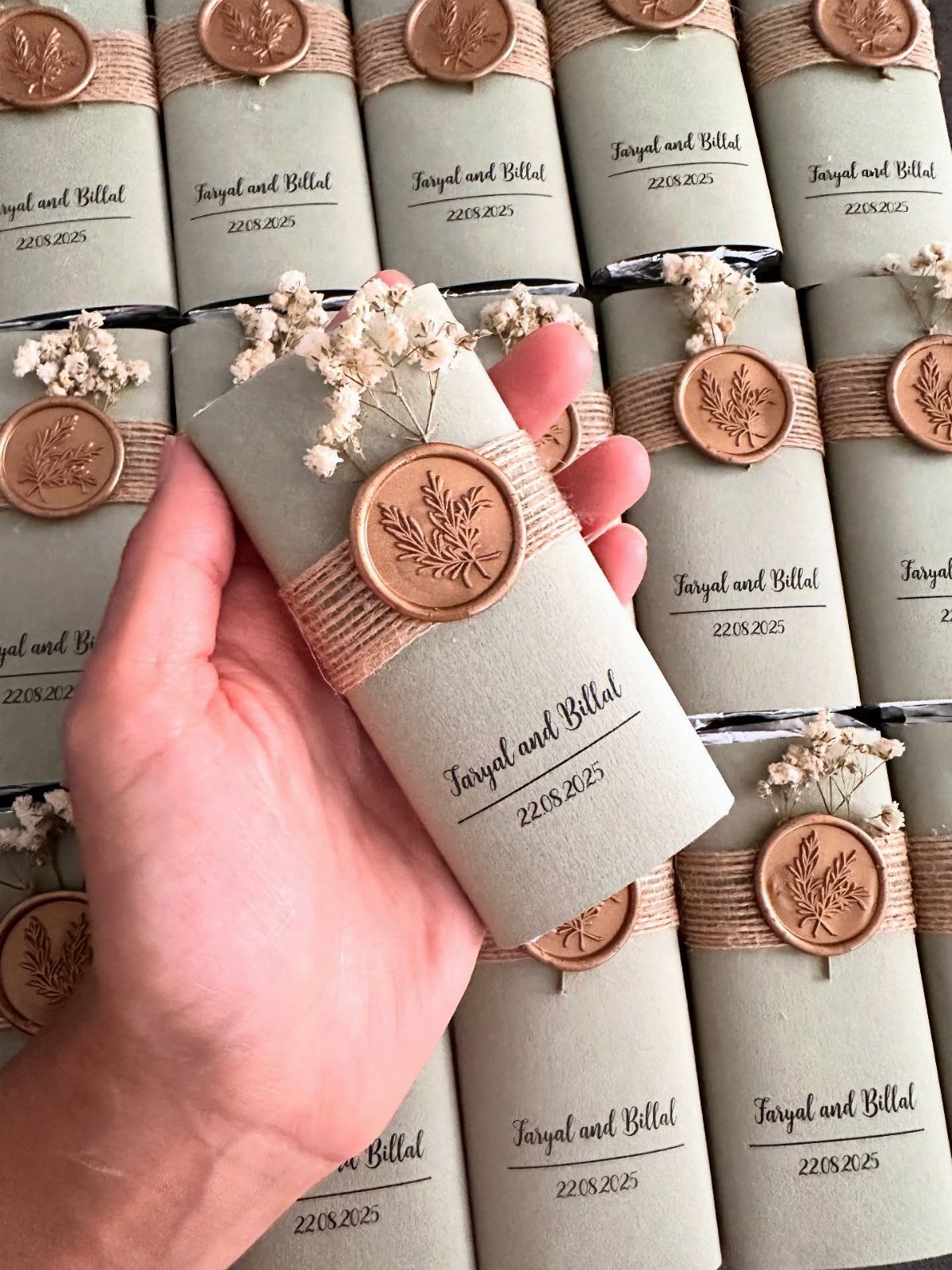 Hand holding a grey wrapped wedding favor with twine and copper wax seal