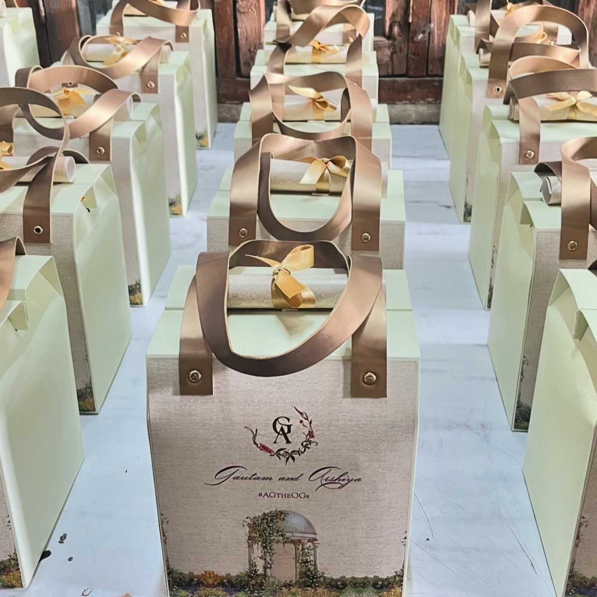 Personalized cream gift bags with gold handles and custom wedding labels on white surface