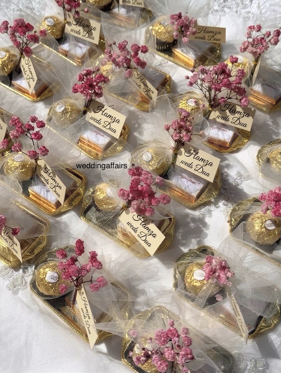 Small gold trays with chocolates and cake wrapped in tulle for wedding gifts.
