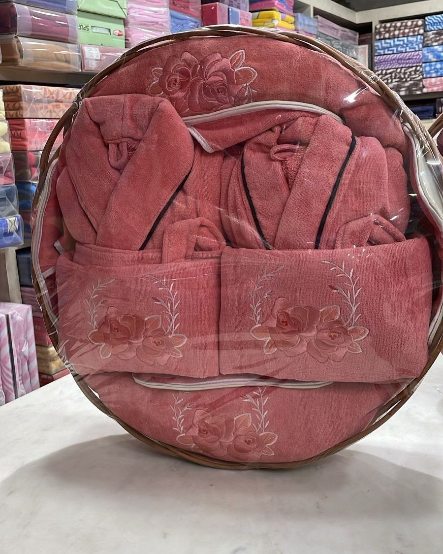 Pink embroidered towel and robe set arranged in a round gift basket