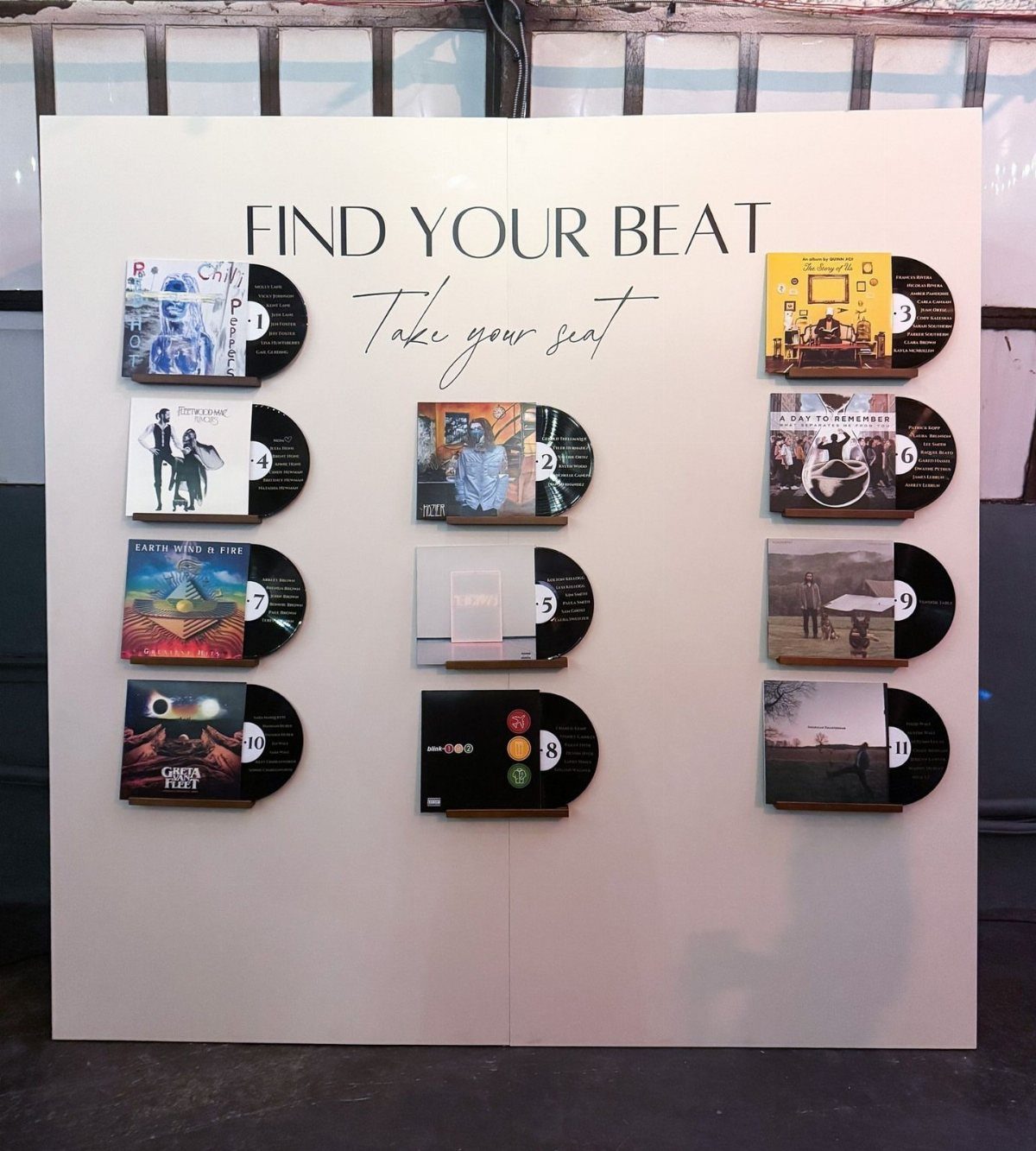 Vinyl records in sleeves arranged on a white wall as a seating chart