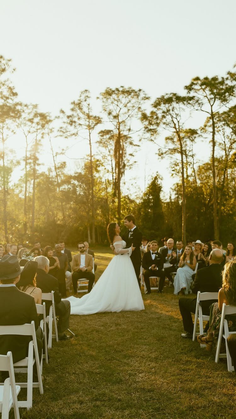 Bride and groom embracing during a wedding ceremony with guests in theatre-style seating.