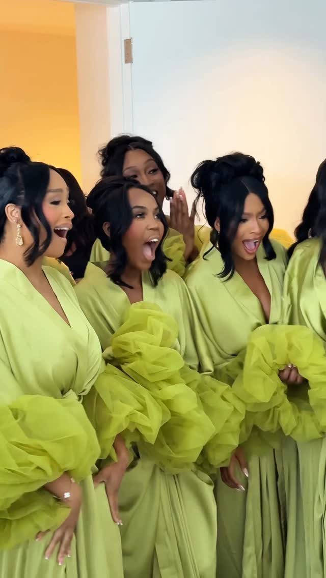 Women in lime green satin robes holding fluffy green tulle fabric and smiling.
