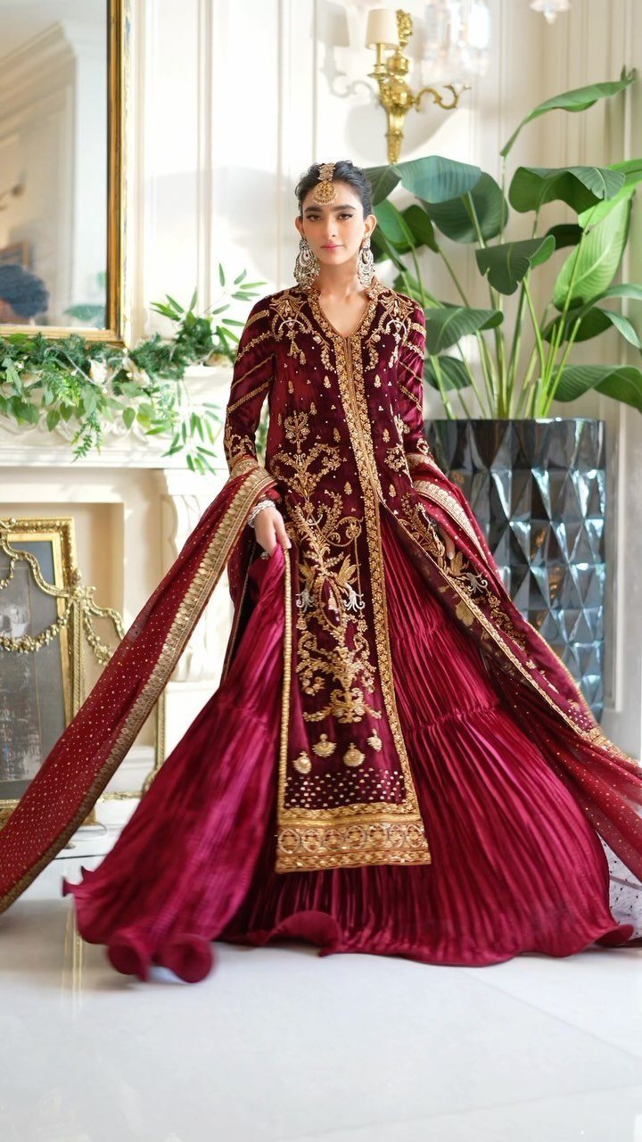 Woman in deep red and gold embroidered traditional dress standing in bright room