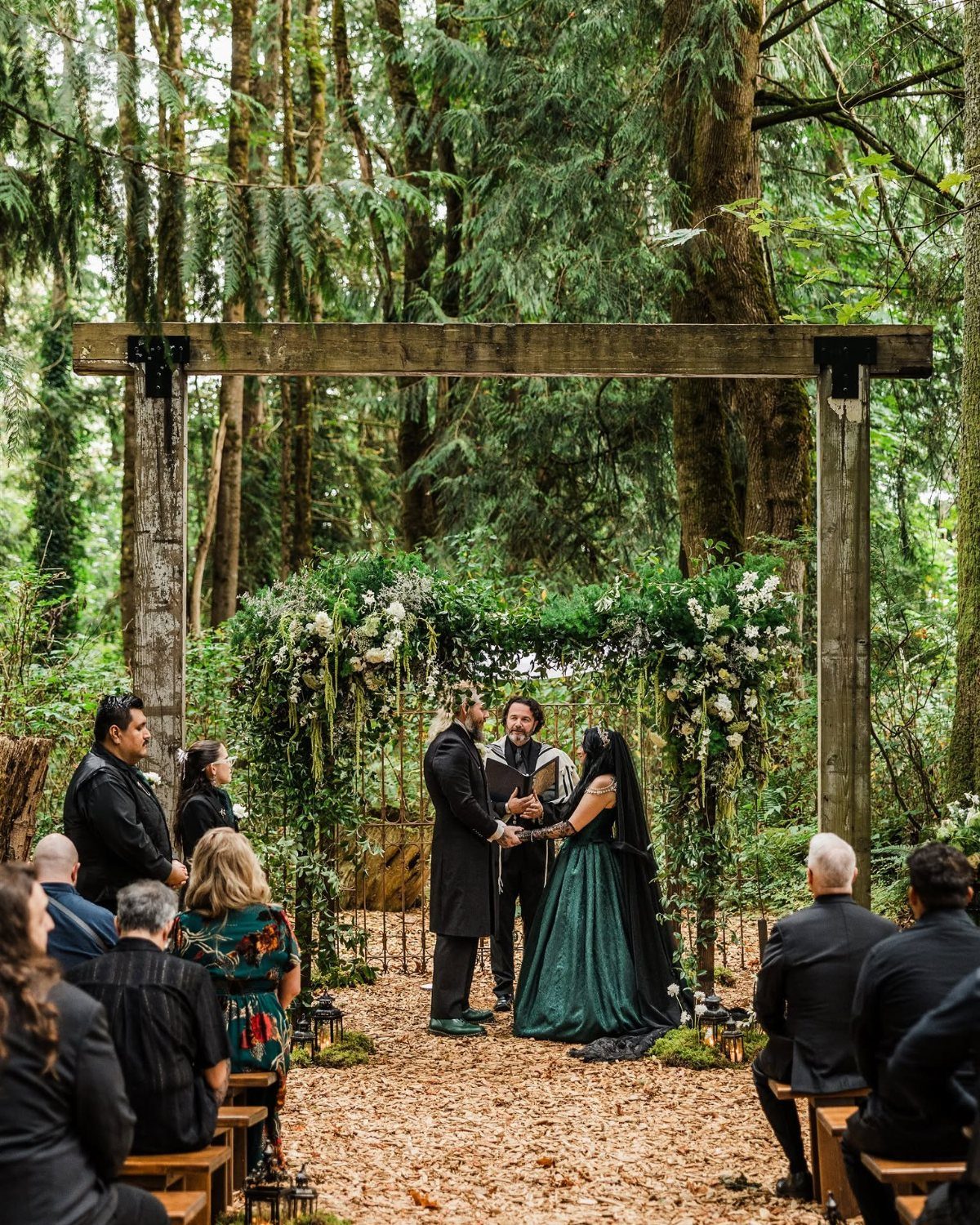 Bride in forest green gown and groom in black suit at woodland wedding