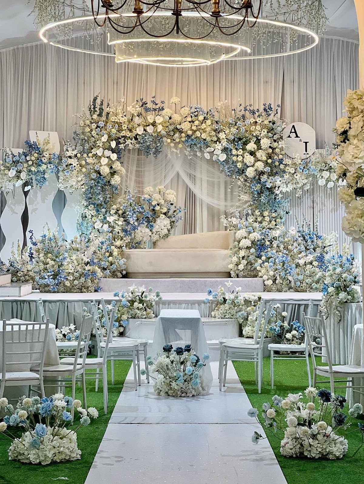 Wedding ceremony setup with white and ice blue floral arch and white chairs.