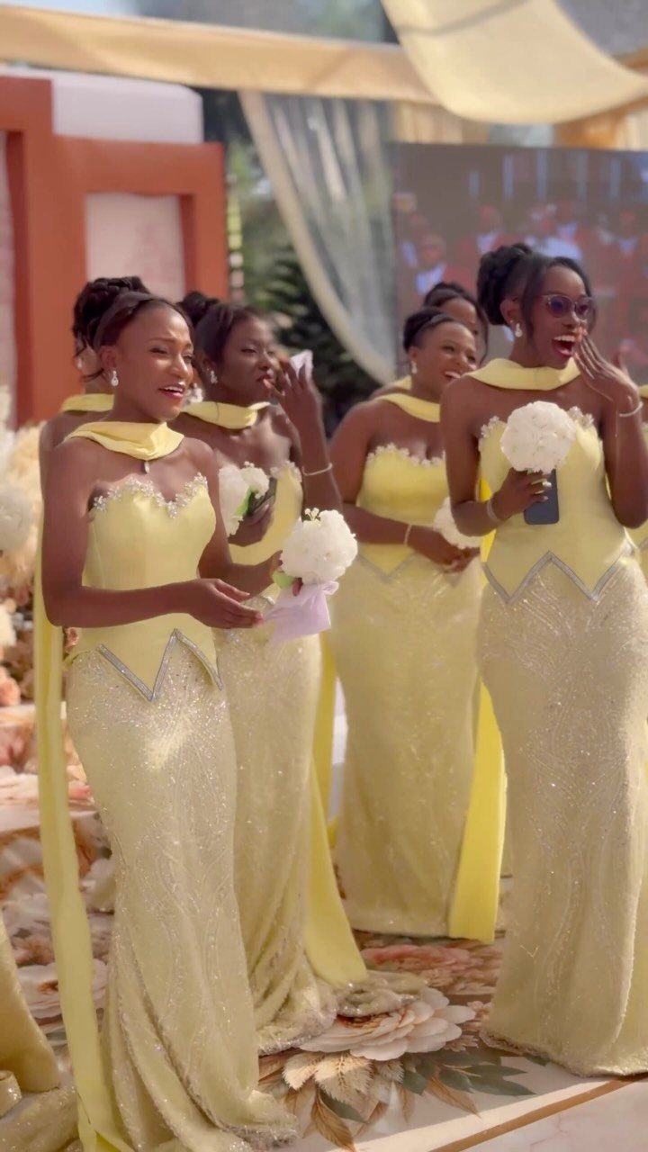 Four bridesmaids wearing shimmering butter yellow floor-length gowns at an outdoor wedding event.