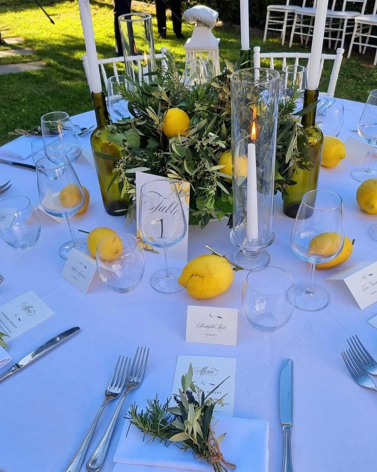 Wedding table centerpiece with green eucalyptus leaves, yellow lemons, and white candles.